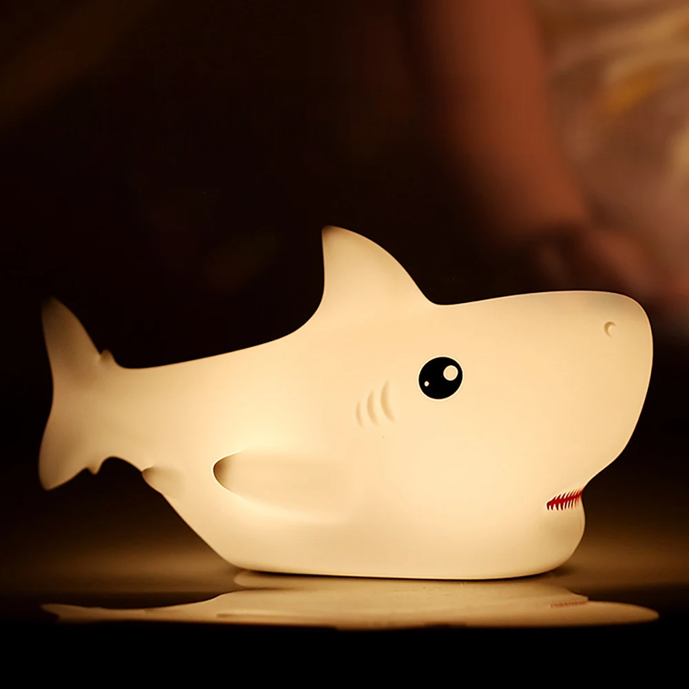 Shark-shaped night light emitting a warm glow on a dark background
