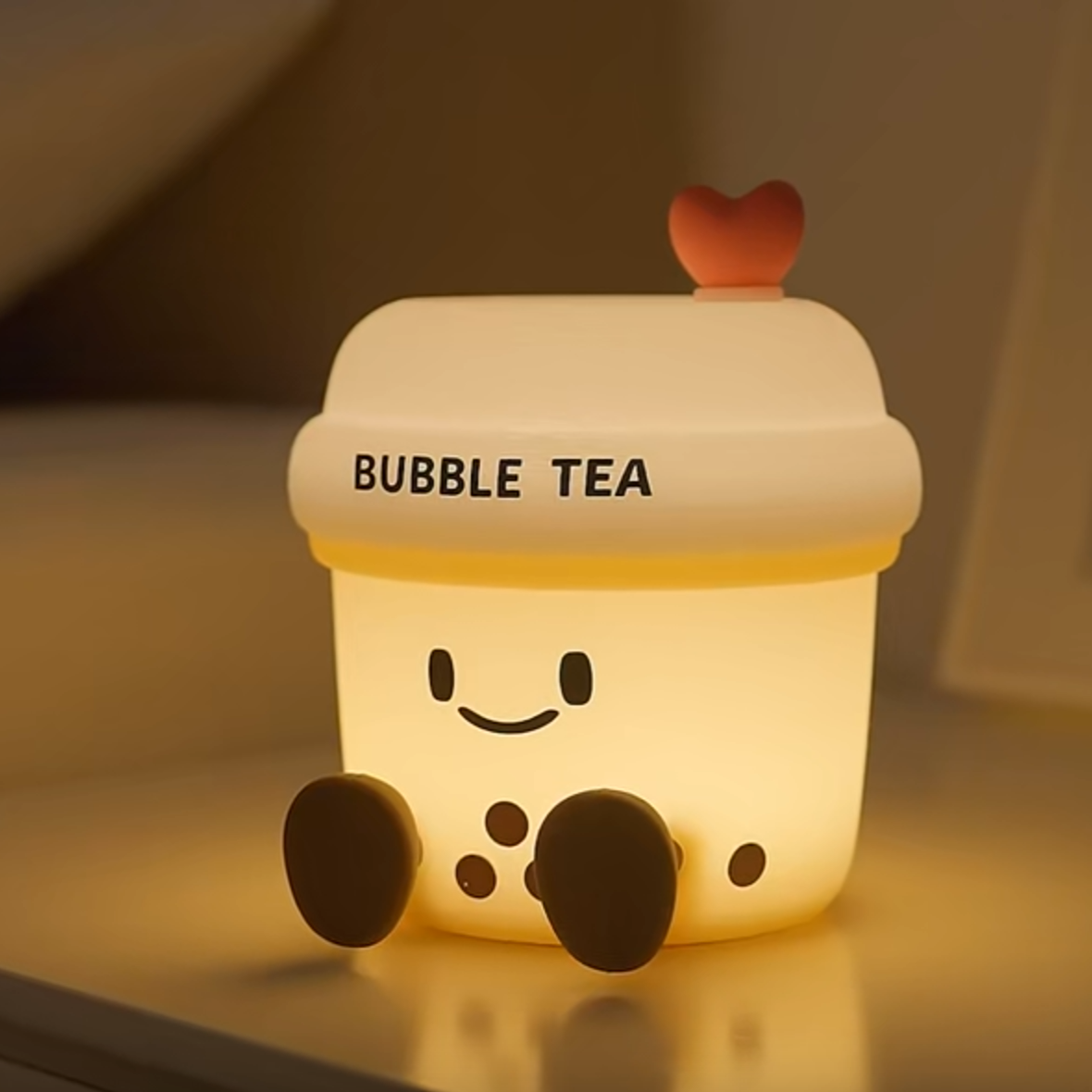 Cute bubble tea-shaped night light with a smiling face on a reflective surface.
