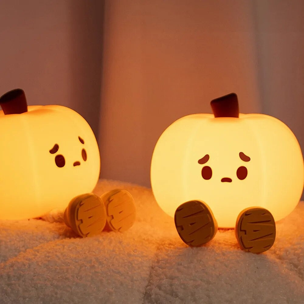Two LED Night Light Lamp pumpkins looking sad sitting on a pillow
