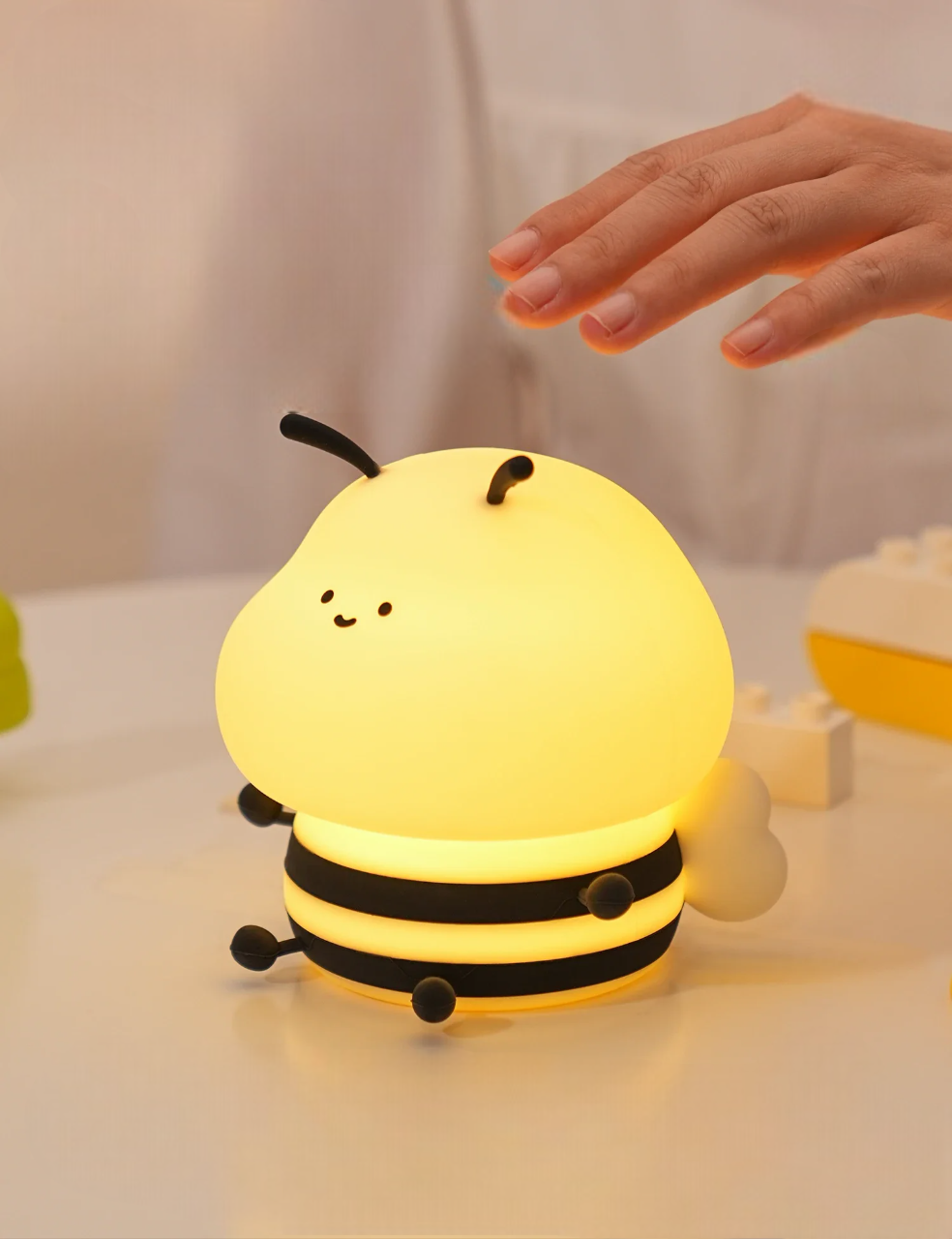 Bumble Bee LED Light glowing on a table with a hand about to squish it to turn the bee lamp off