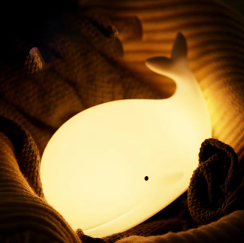 LED Lamp shaped like a Whale glowing in a bundle of blankets