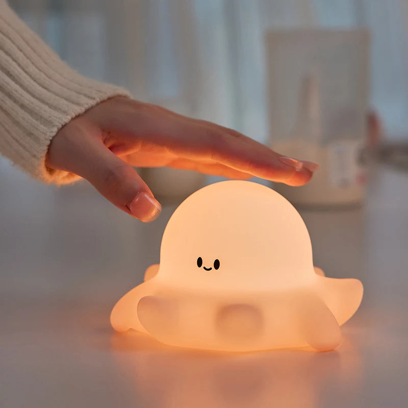 Cute ghost-shaped night light being held by a hand with a blurred background