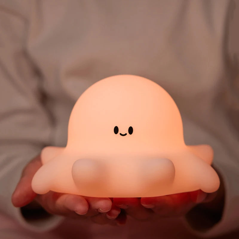 Cute, glowing octopus-shaped night light held in hands against a neutral background