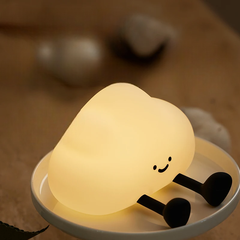 Cute lamp shaped like a cloud with a smiling face on a wooden surface