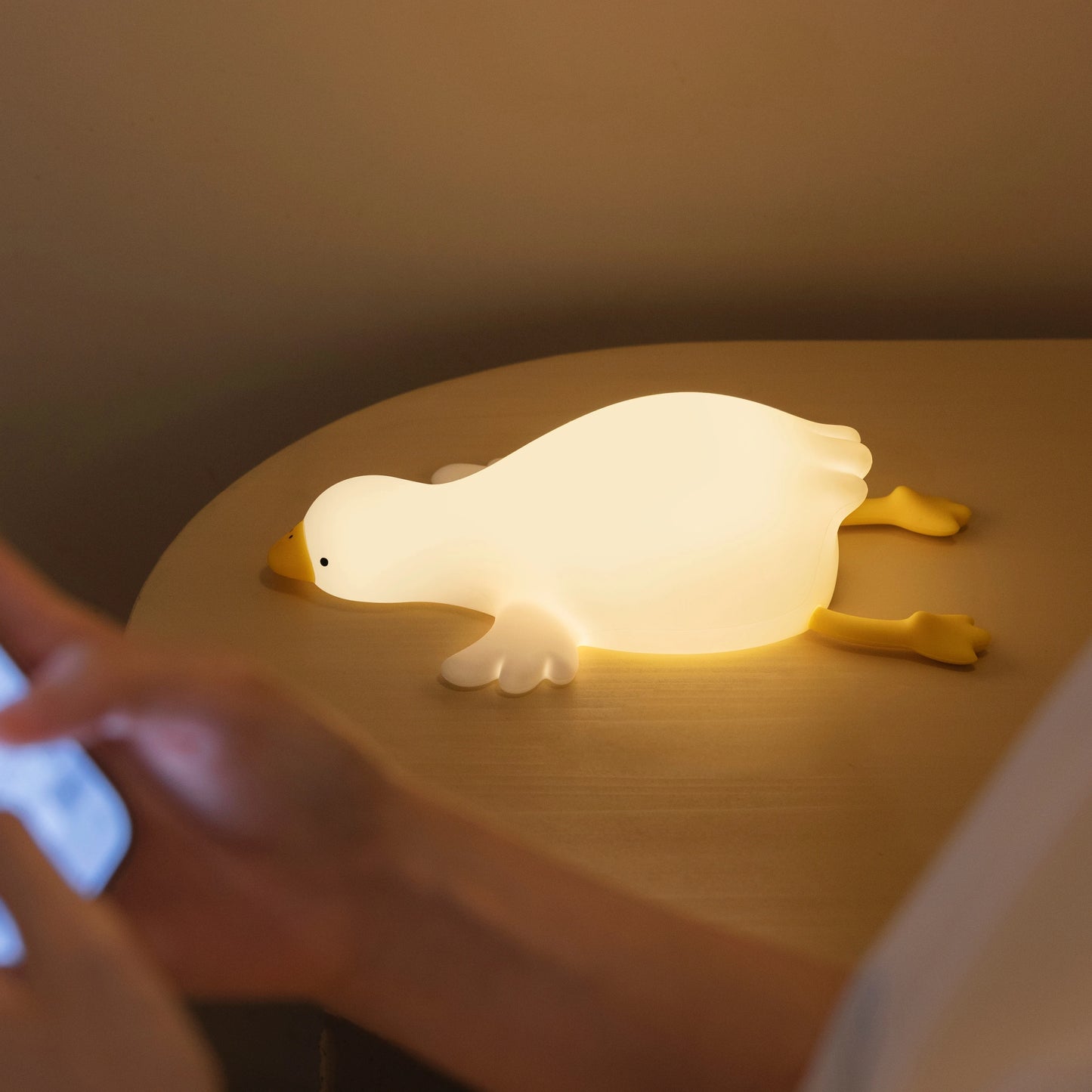 Warm glowing goose shaped nightlight on a bedside table