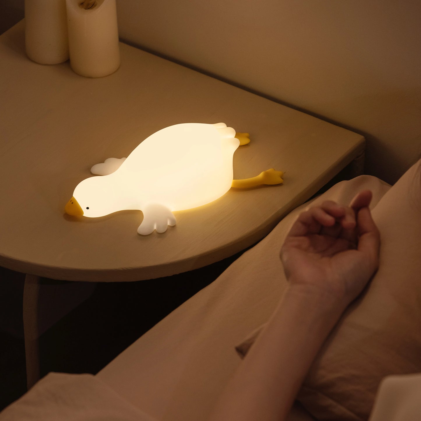 Glowing Goose night light on table beside sleeping child on bed