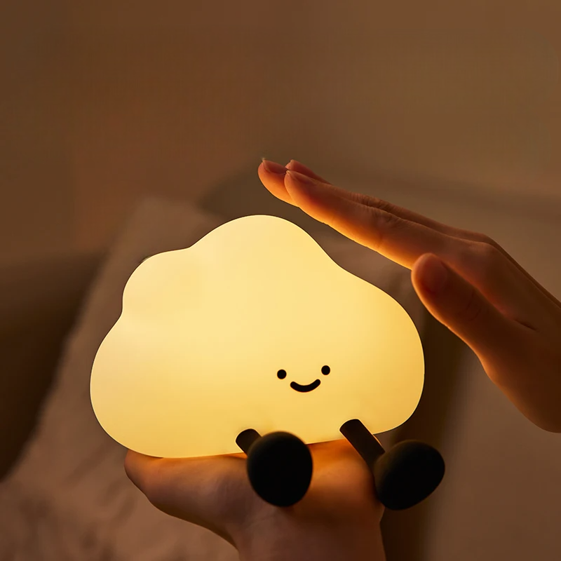 Glowing cloud-shaped night light held by a hand with a warm, soft glow.