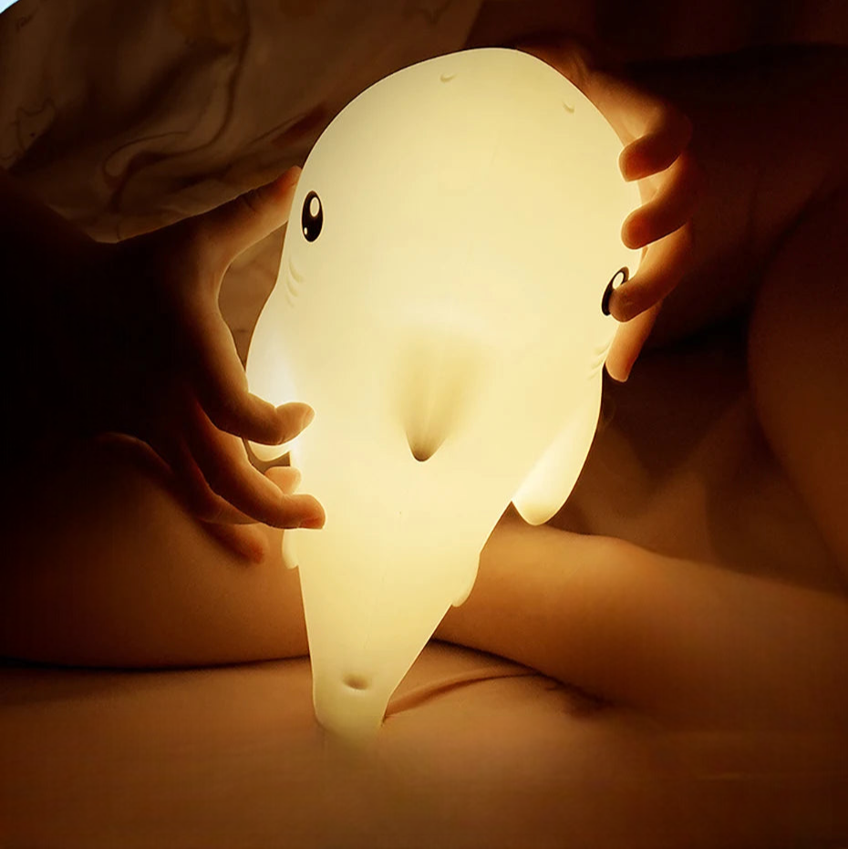 Children's hands holding a glowing shark-shaped night light.
