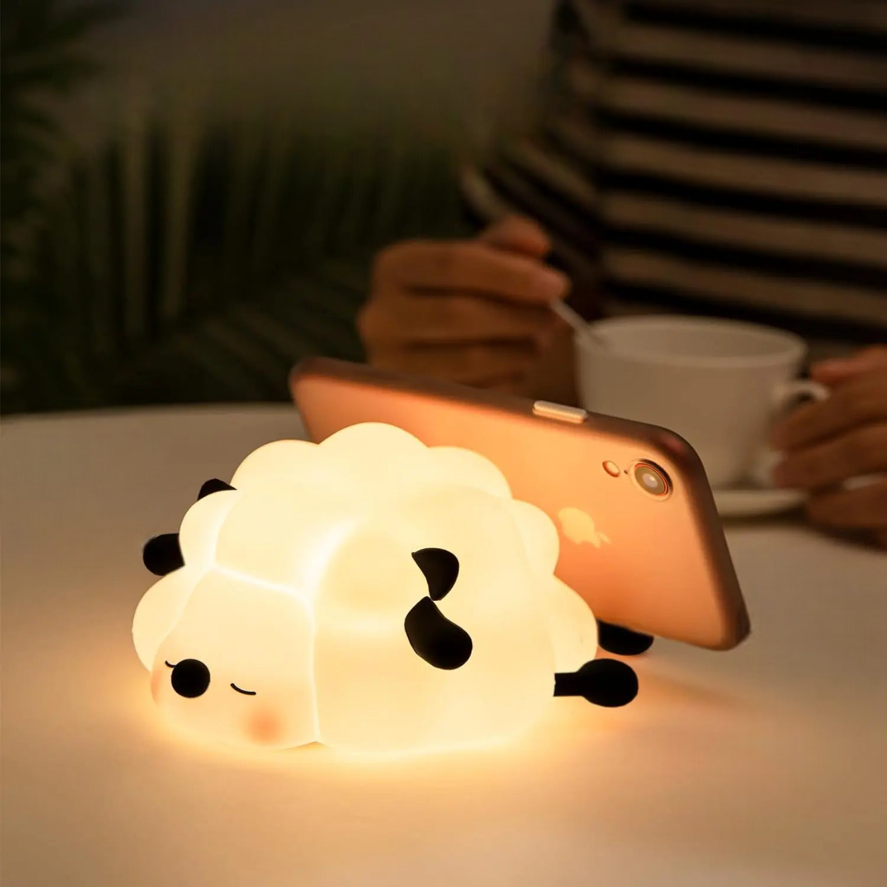 Sleeping Sheep LED shaped lamp glowing on a table with an iphone placed against it