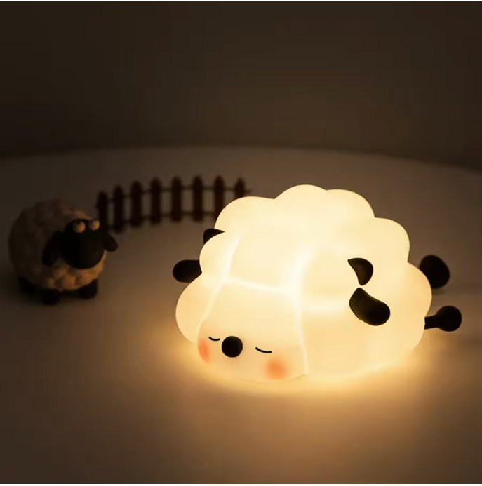 Sheep Shaped LED Lamp Glowing on a Table with a Porcelain Sheep and small wooden fence
