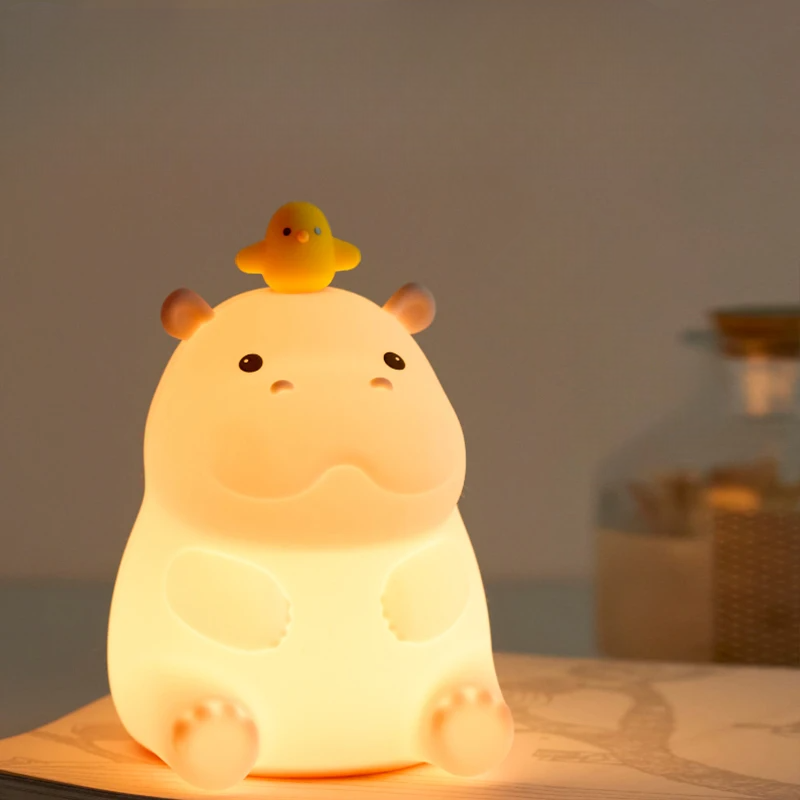 Teacup Hippo-shaped night light with a small yellow duck on its back, glowing softly.