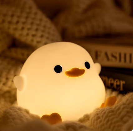 LED Night Light Lamp duck sitting on a blanket next to two books