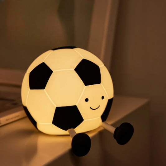Soccer ball-shaped night light with a smiling face on a shelf.
