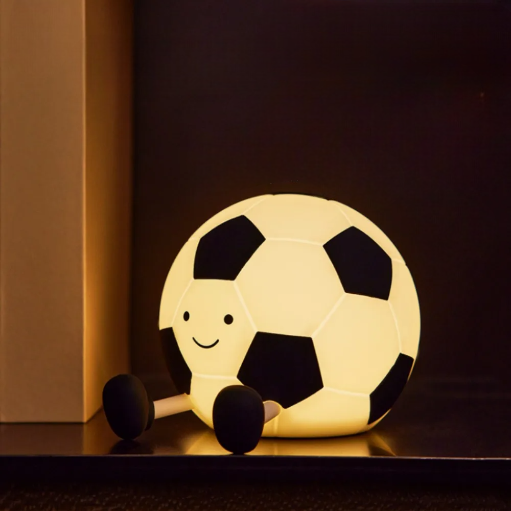 Soccer ball-shaped night light with a smiley face on a dark background