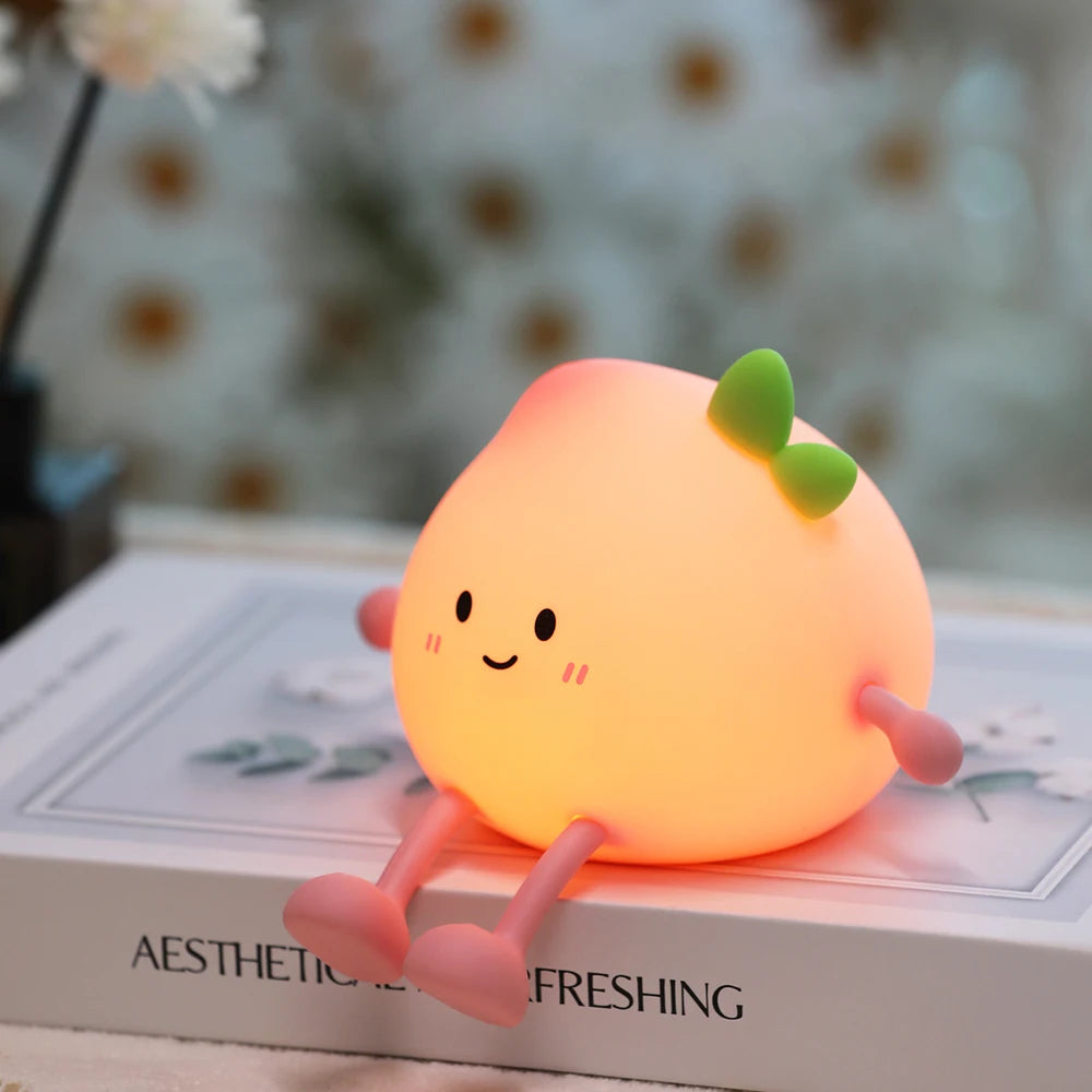 Cute peach-shaped night light with a smiling face on a book