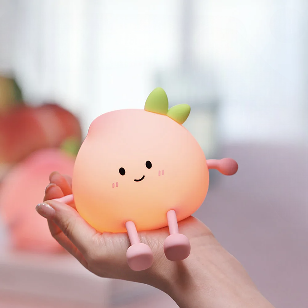 Cute peach-shaped night light held in a hand with a blurred background