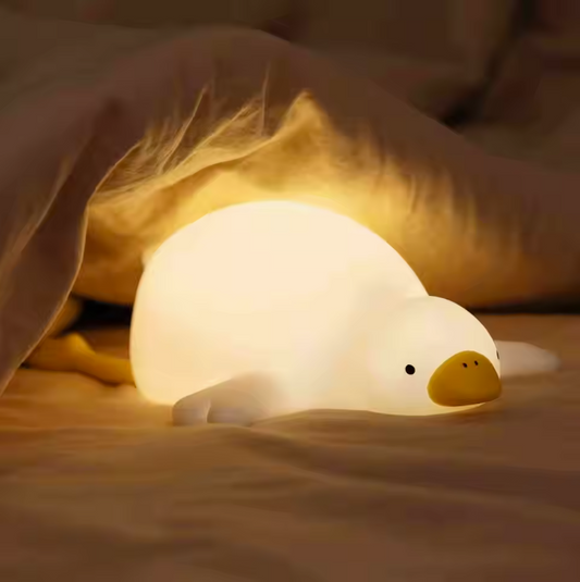goose shaped nightlight glowing warmly under blankets on bed