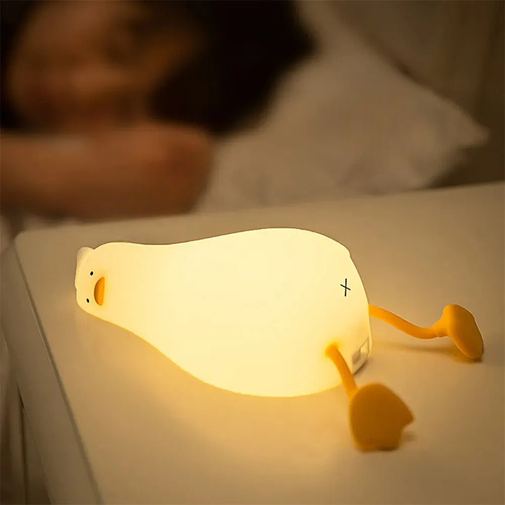 LED Night Light Lamp duck laying on a night stand with a person sleeping in background