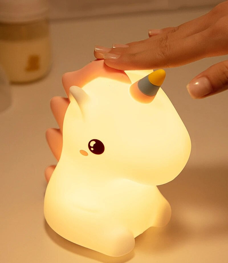 Unicorn Lamp on a table being pressed on by a women's hand