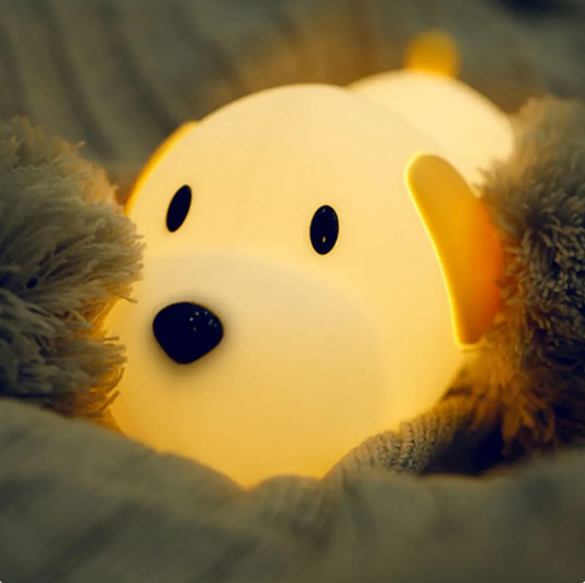 Dog shaped Led Night light lamp laying on a bed with blanket