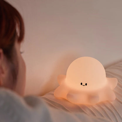 Person lying on a bed with a cute ghost-shaped night light emitting a warm glow.