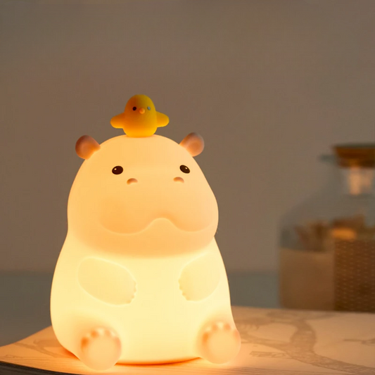Teacup Hippo-shaped night light with a small yellow duck on its back, glowing softly.